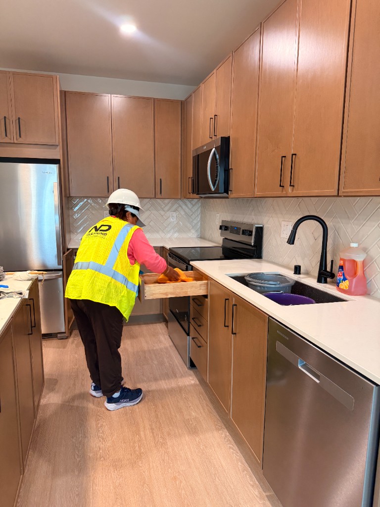 ND Cleaning crew member detailing cabinets and drawers during a final construction clean in a new kitchen